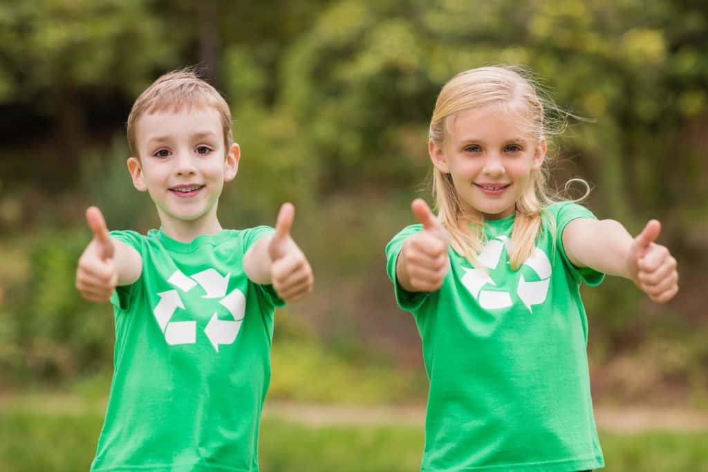 Happy siblings in green with thumbs up on a sunny day